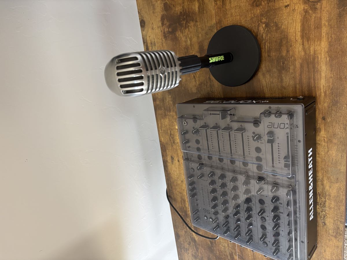 An Allen & Heath mixer under a dust cover beside a chrome Shure microphone.